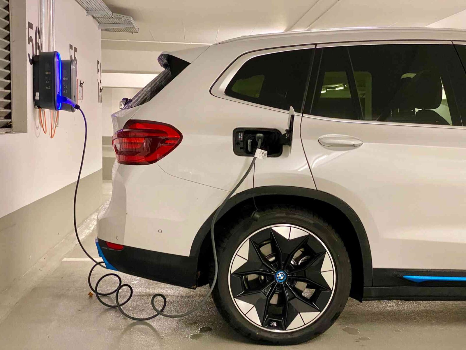 white BMW being charged in a carpark