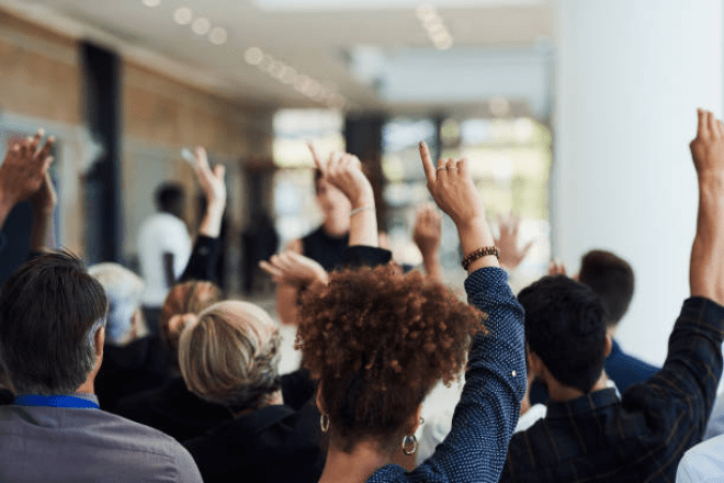 Audience With Raised Hands During a Conference